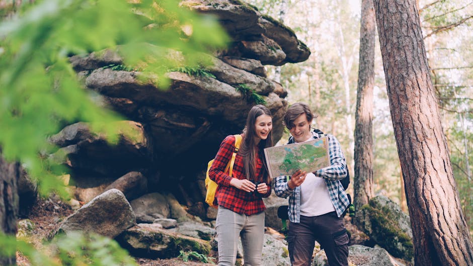 A happy couple in a forest using a map to navigate during their outdoor adventure.