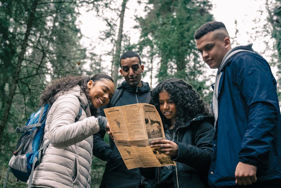 Diverse group of friends hiking in the forest, examining a map together.