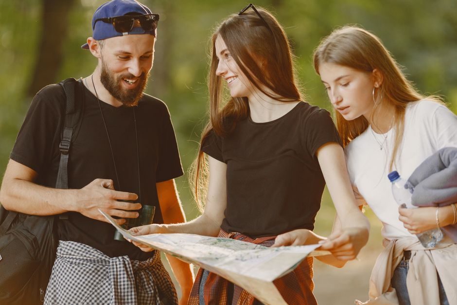 A group of friends enjoying an outdoor adventure and examining a map together.