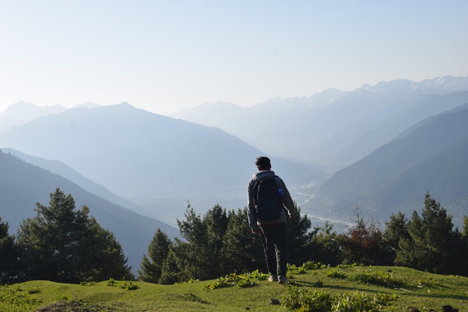 Solo hiker overlooks vast mountainous landscape, basking in nature's beauty.